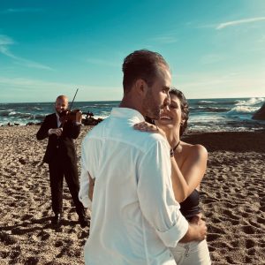 Violinist crafting a distinctive romantic ambiance during the beachside marriage proposal