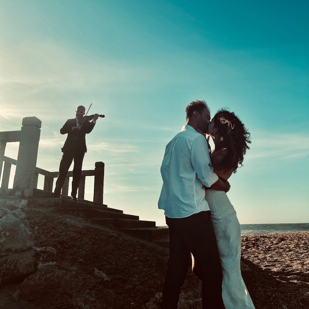 Violinist creating a unique romantic atmosphere during the marriage proposal on the beach